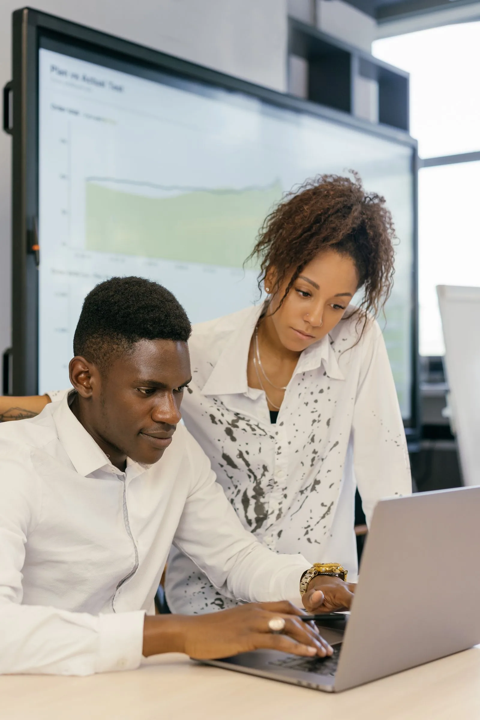Two people reviewing work together on a laptop